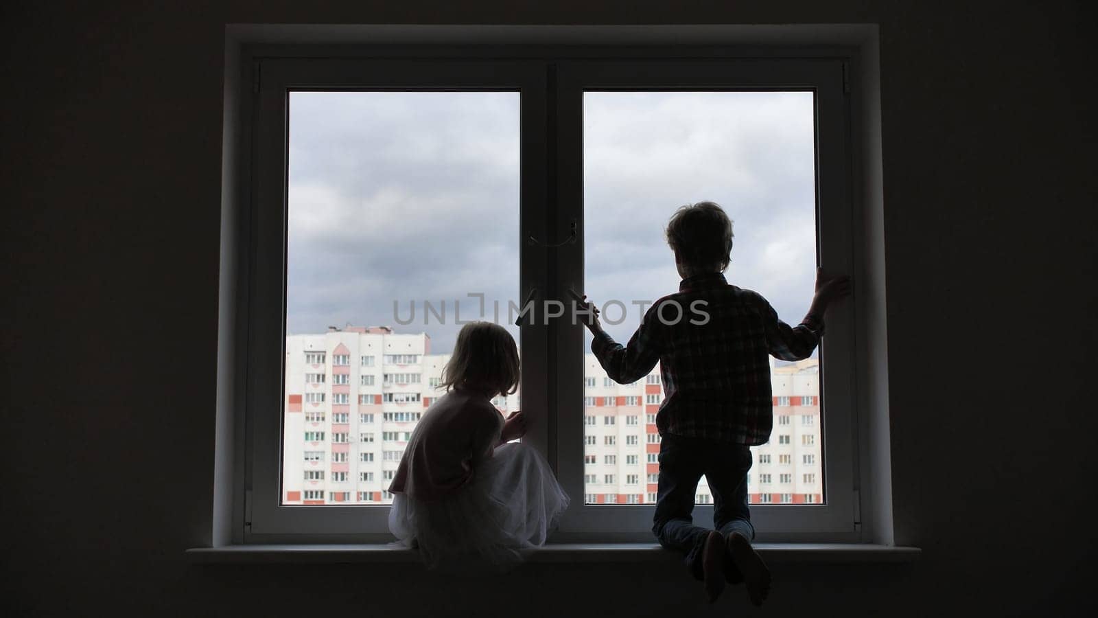 Silhouette of children on the background of a window in the apartment
