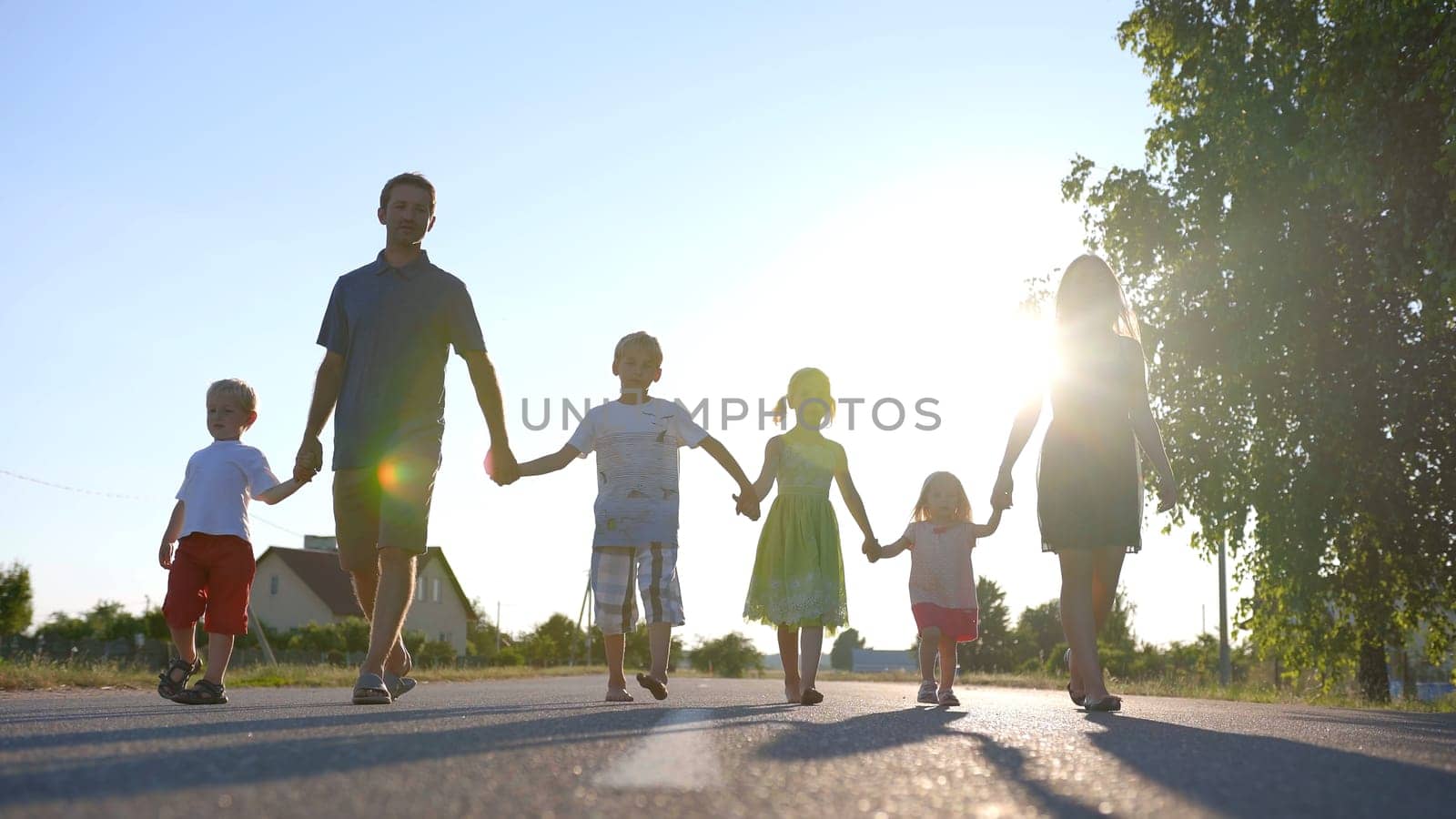 Strong friendly family holding hands goes along the road. by DovidPro