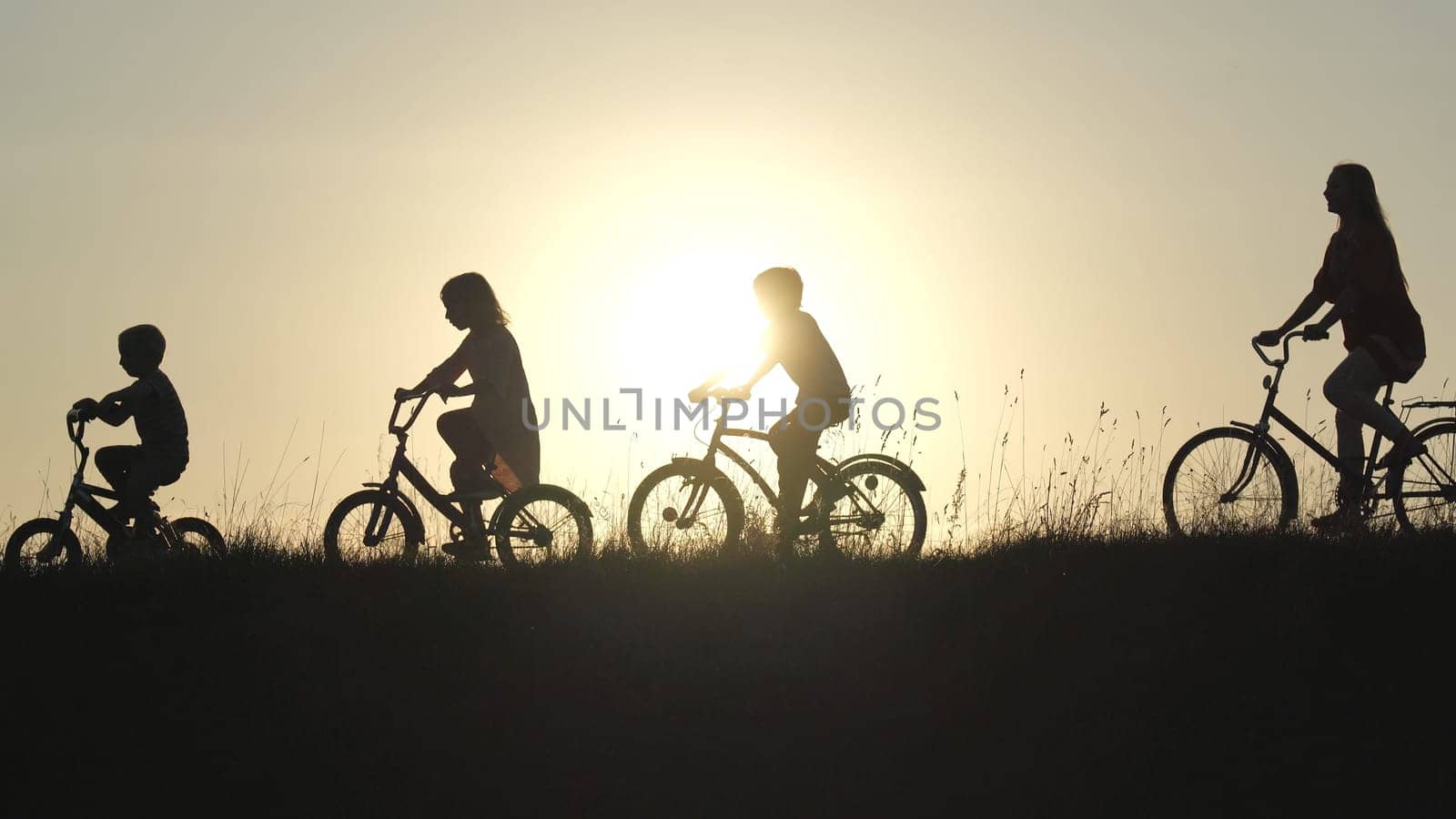 Silhouettes of a large large family on bicycles at sunset