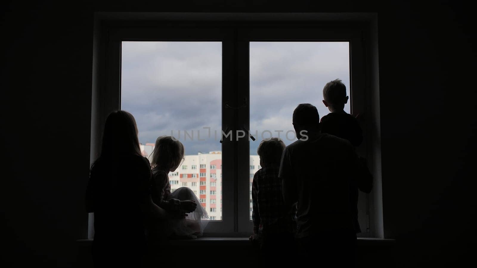 Silhouette of a large family on the background of a window in a new apartment