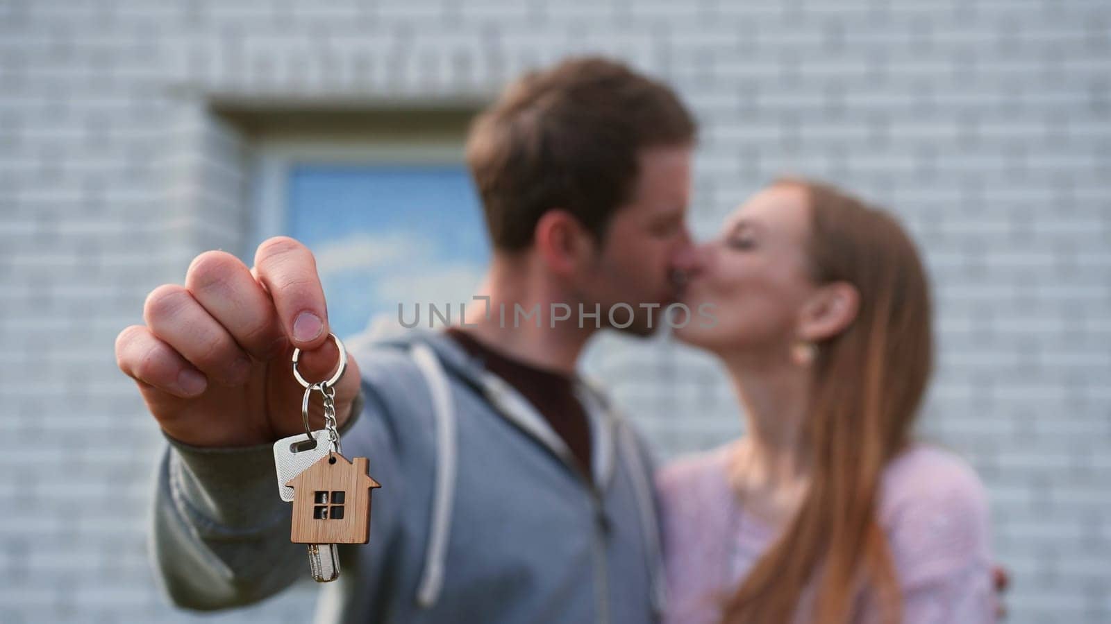 Real estate purchase concept. Young spouses show off the keys to the purchased new home and kiss