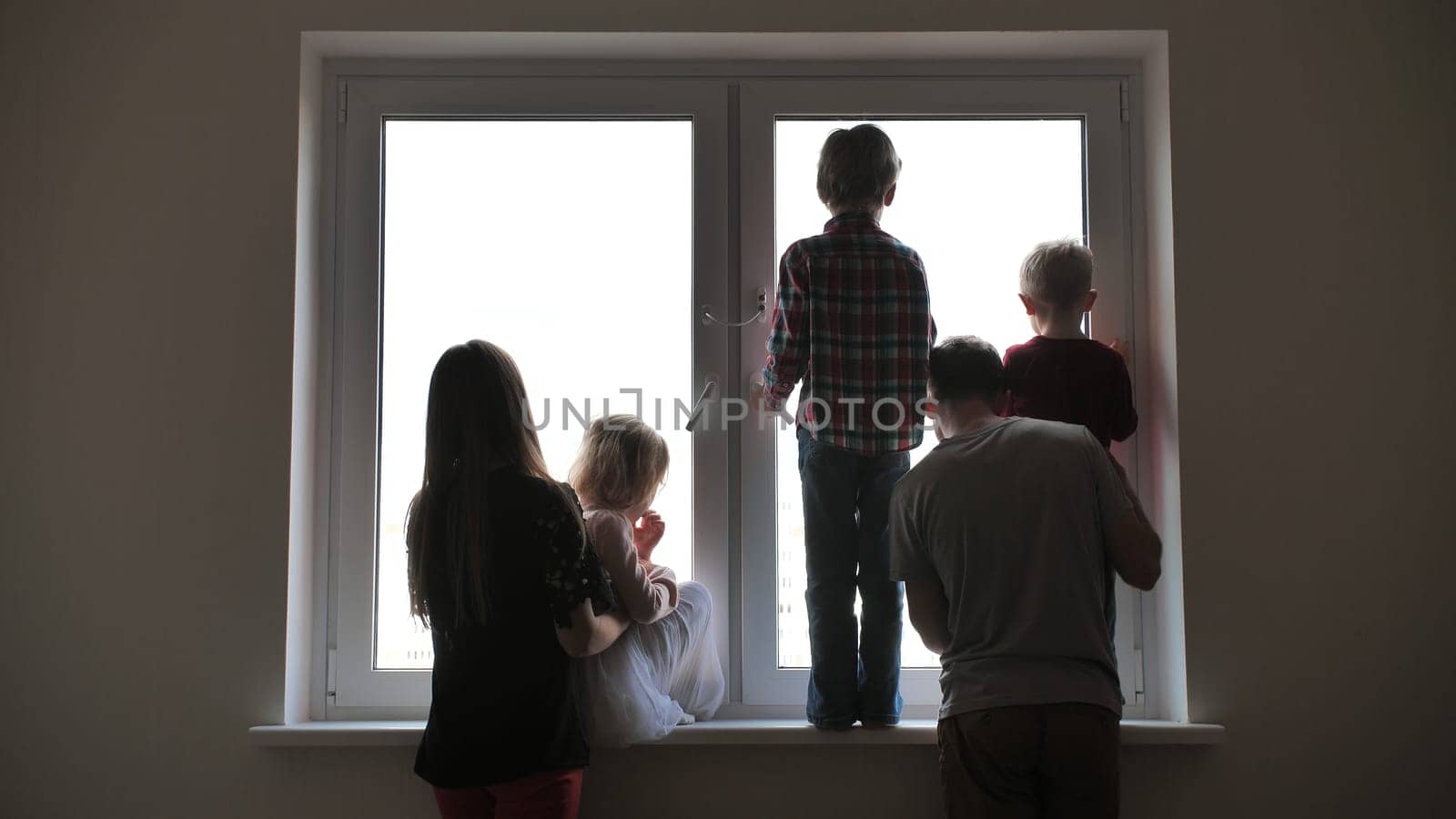 Silhouette of a large family on the background of a window in a new apartment. Quarantine concept