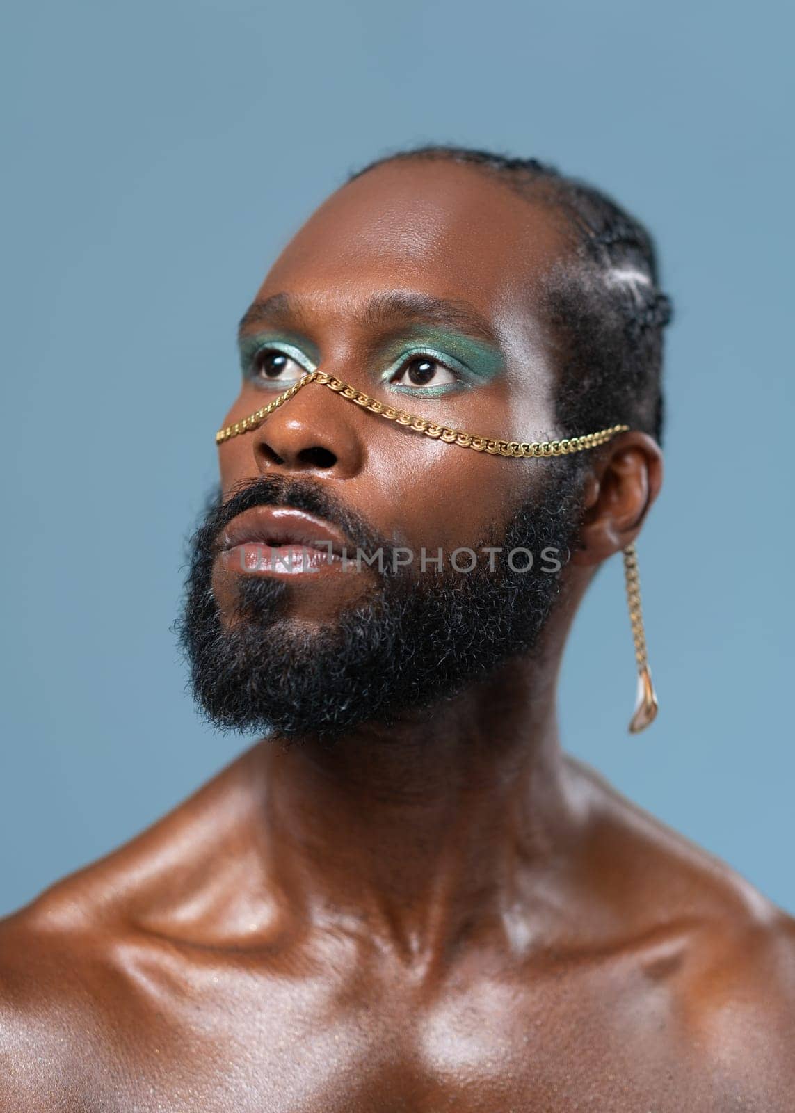 Confident african-american bearded gay man with bright makeup isolated on blue background, Close up portrait. Exudes sense of pride and individuality. Diversity power of personal style.