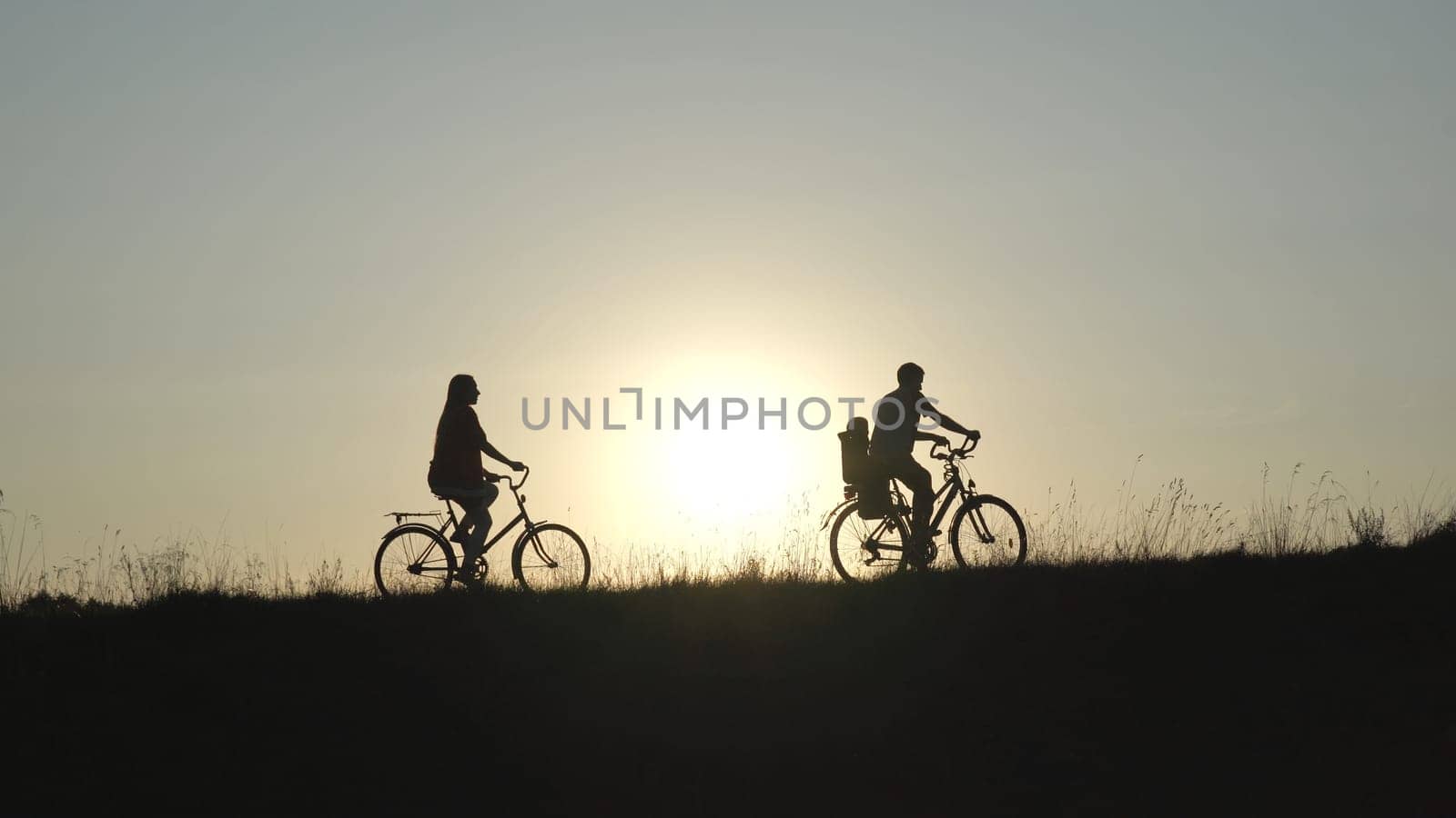 Friendly family with a child on bicycles during sunset. by DovidPro