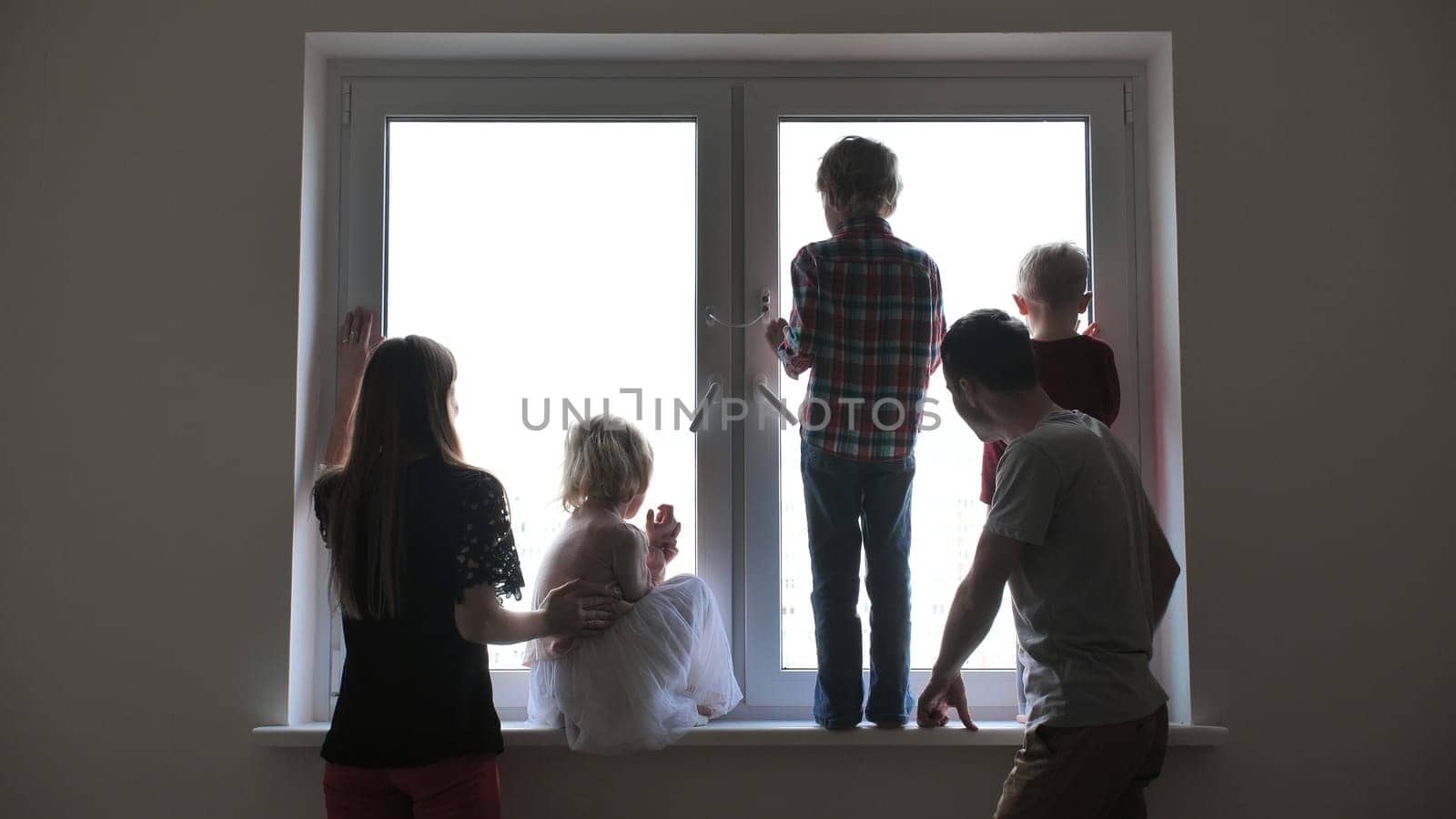 Silhouette of a large family on the background of a window in a new apartment