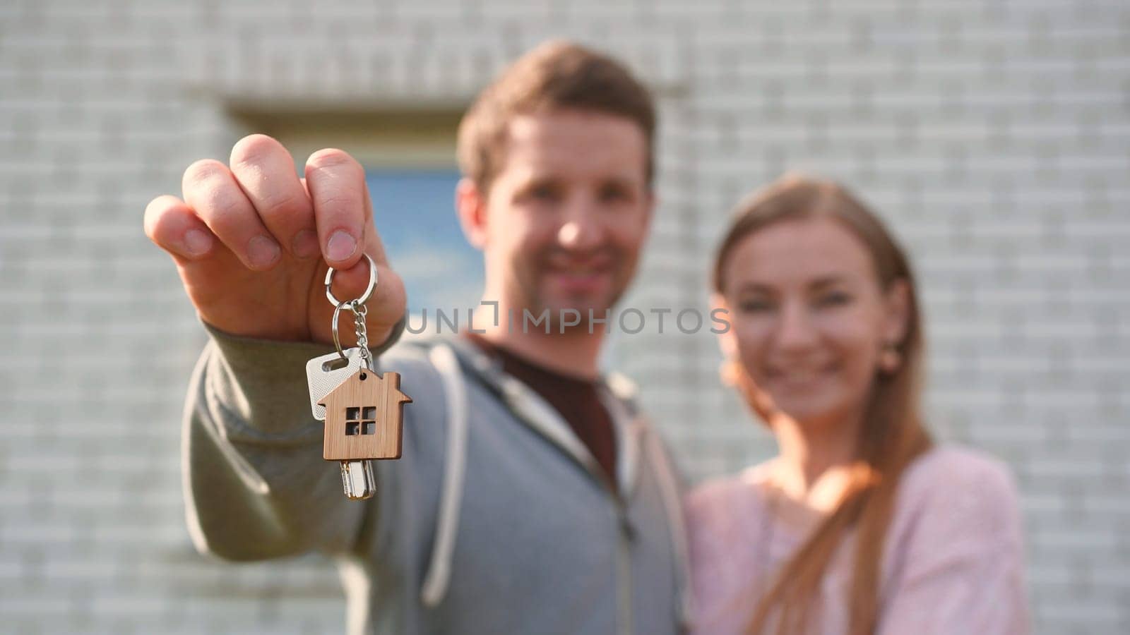 Real estate purchase concept. Young spouses show off the keys to the purchased new home and kiss. by DovidPro
