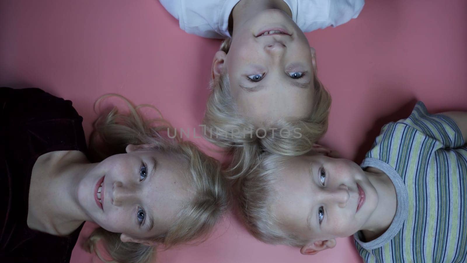 Portrait of little children siblings lying on a pink background
