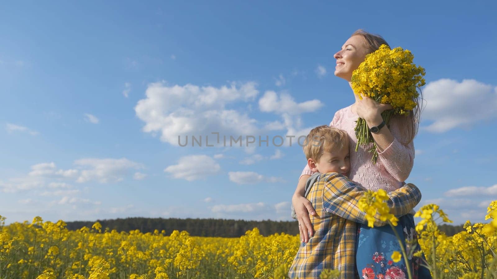 A loving son hugs his mother in a rapeseed field. by DovidPro