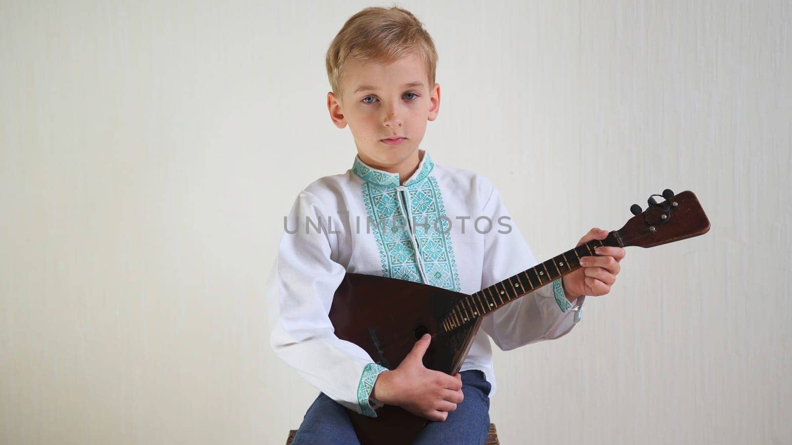 Russian boy in national dress plays the balalaika