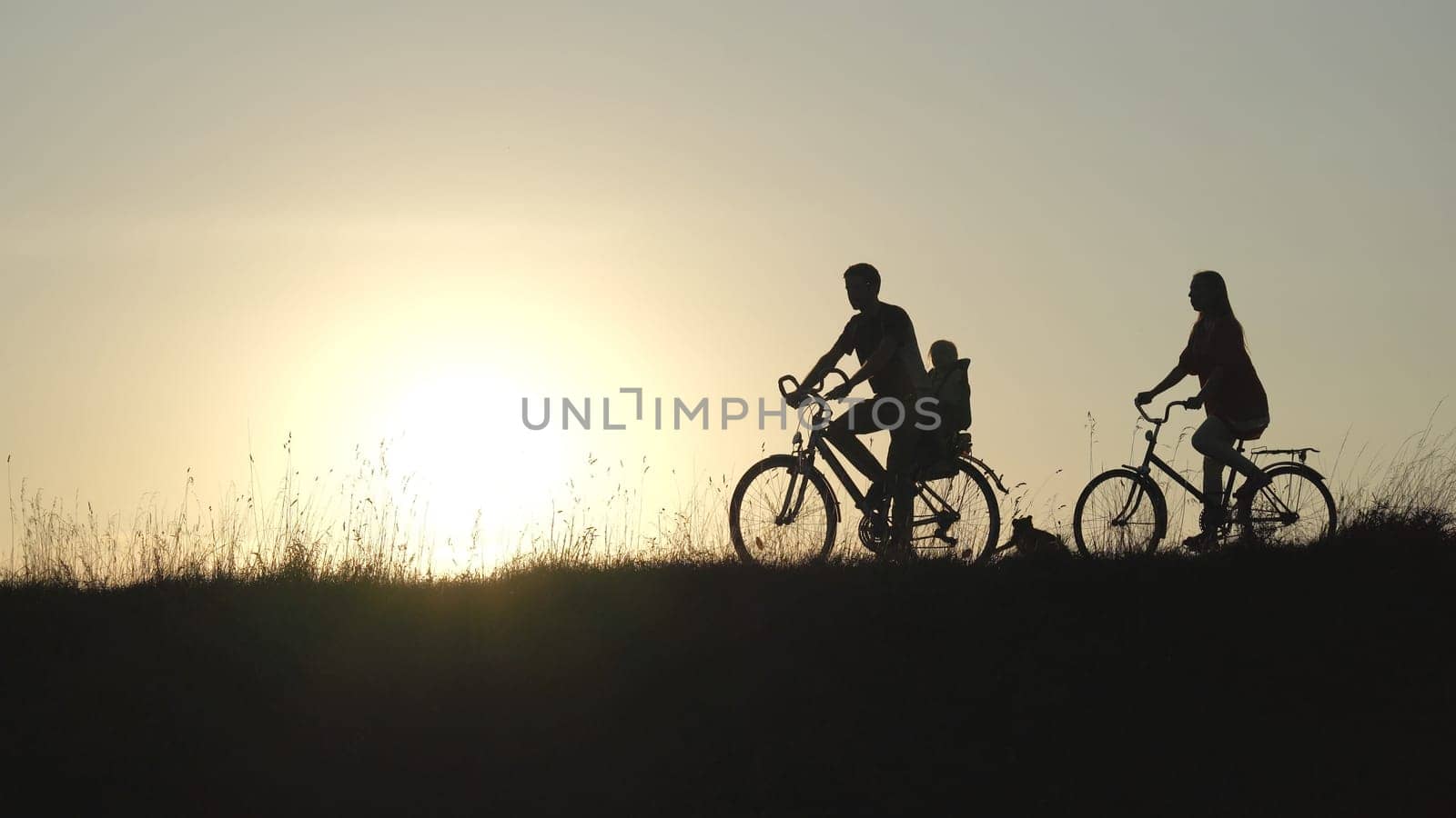 Friendly family with a child on bicycles during sunset