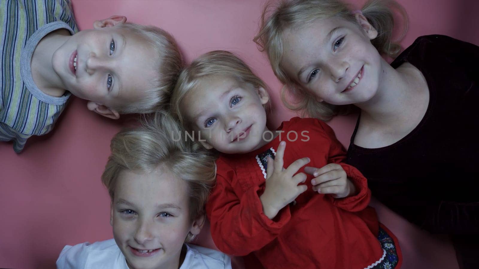 Portrait of little children siblings lying on a pink background