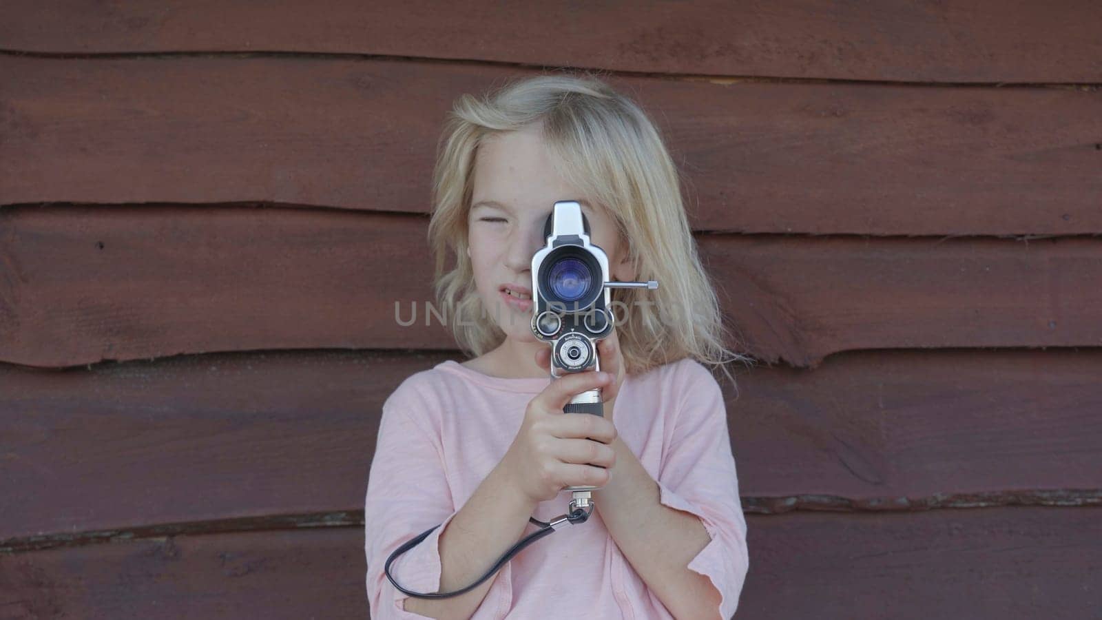 A little girl shoots a video of an old retro camera