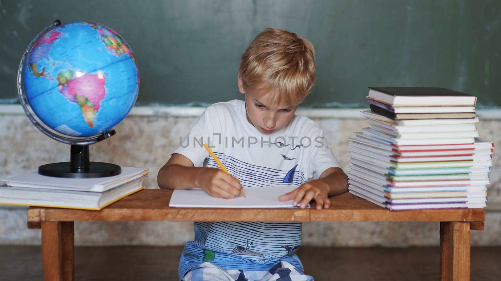 A boy of 8 years old does homework against a background of the globe. Home school concept