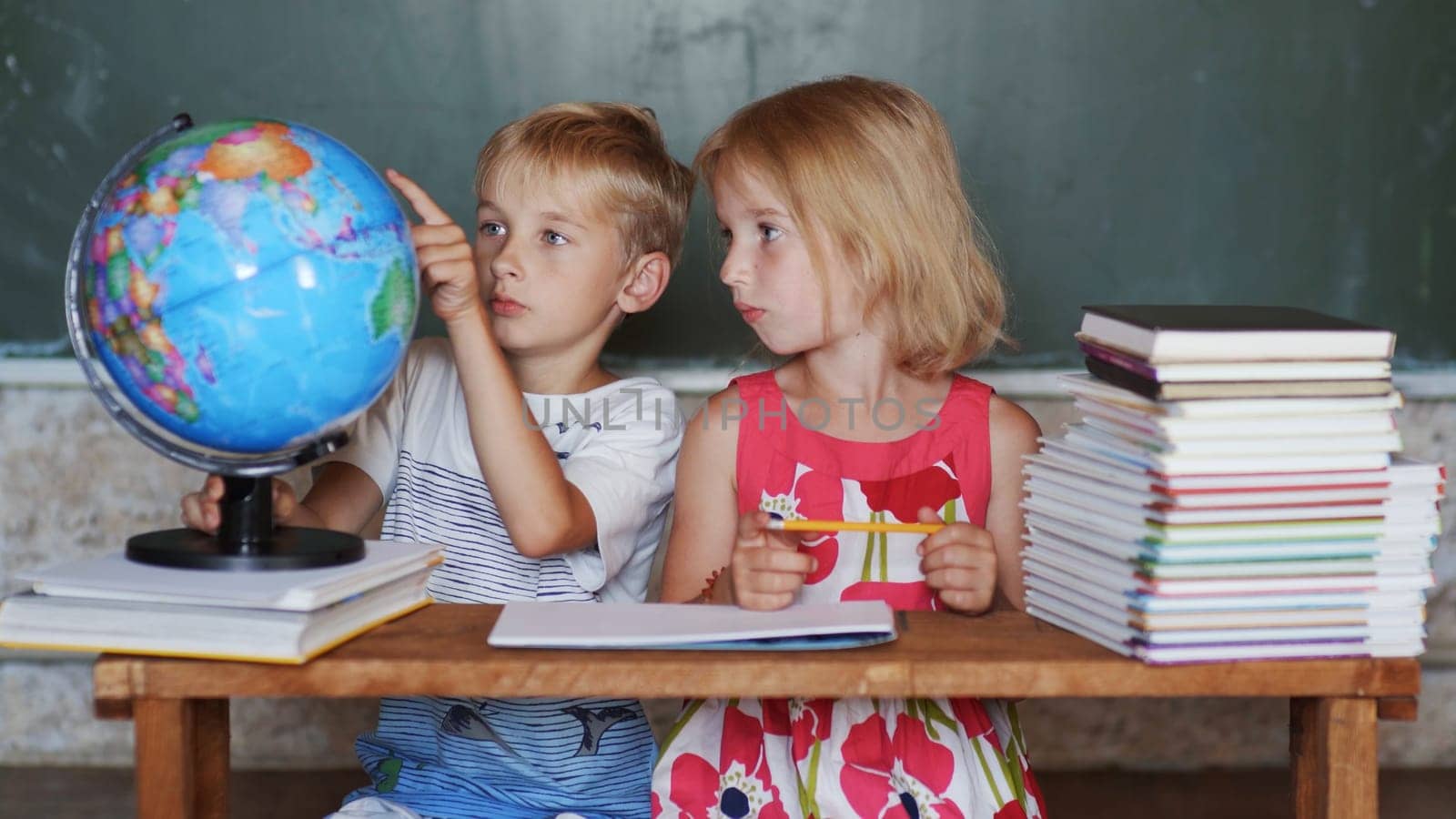 Brother and sister study at home with a world globe. by DovidPro