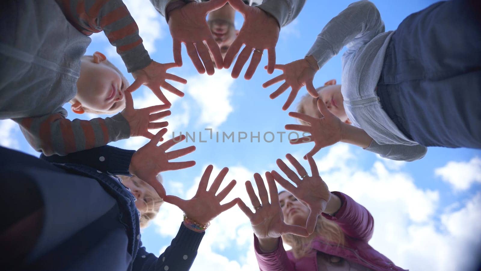 A friendly large family makes a circle shape out of the palms of their hands. by DovidPro