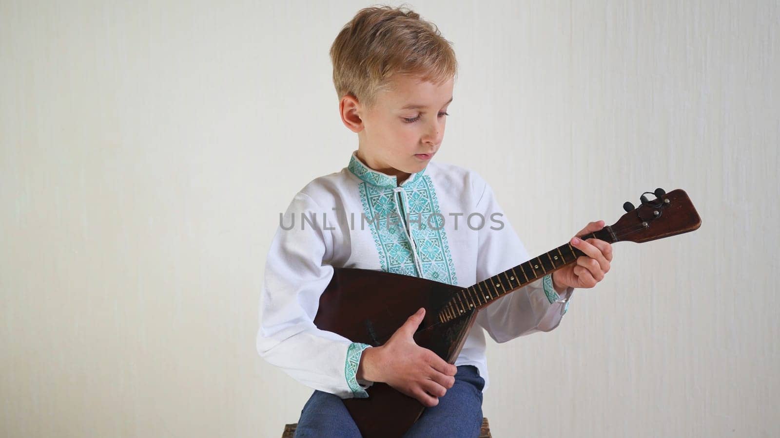 Russian boy in national dress plays the balalaika