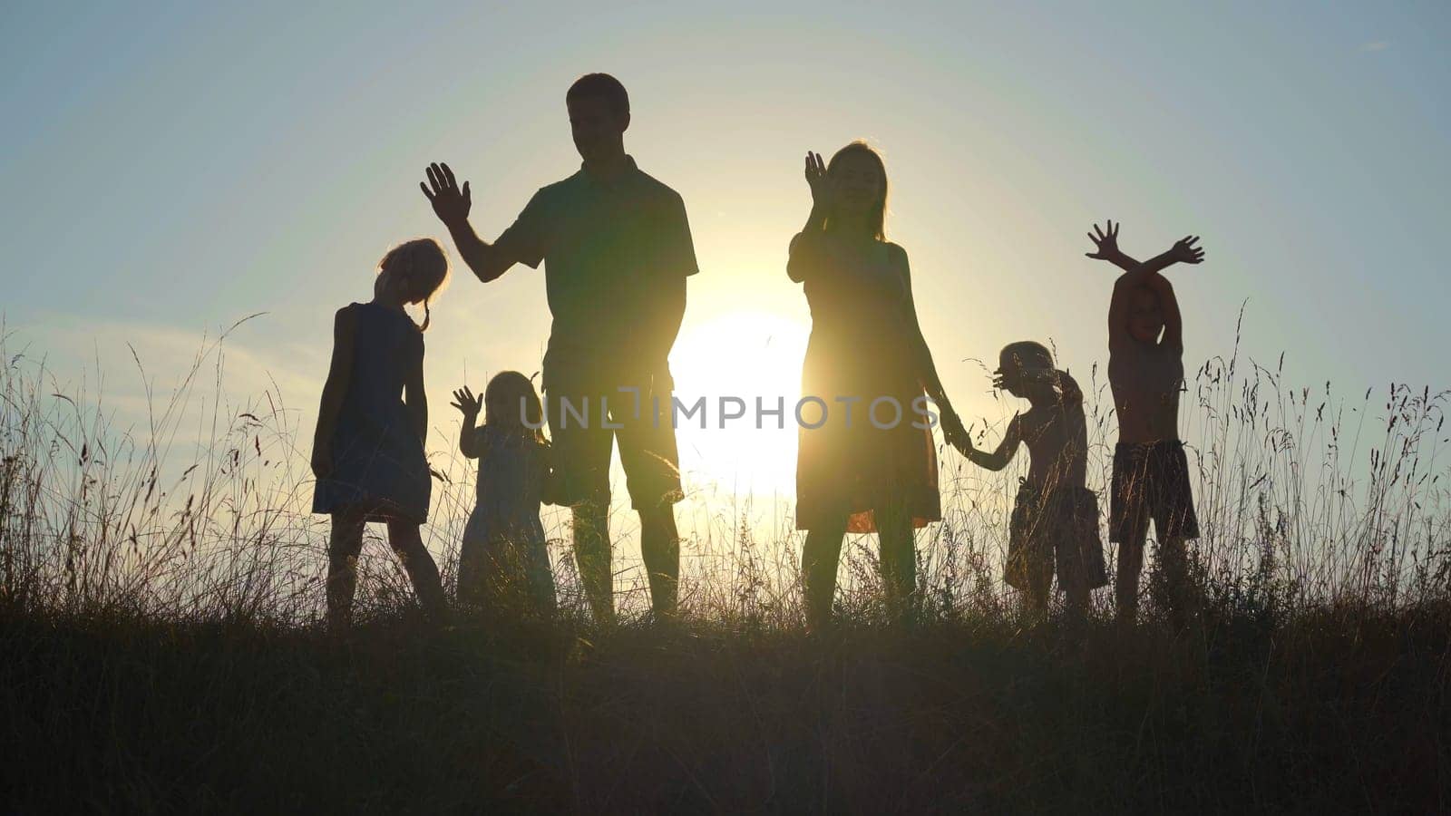 Happy parents with children waving hands at sunset. by DovidPro