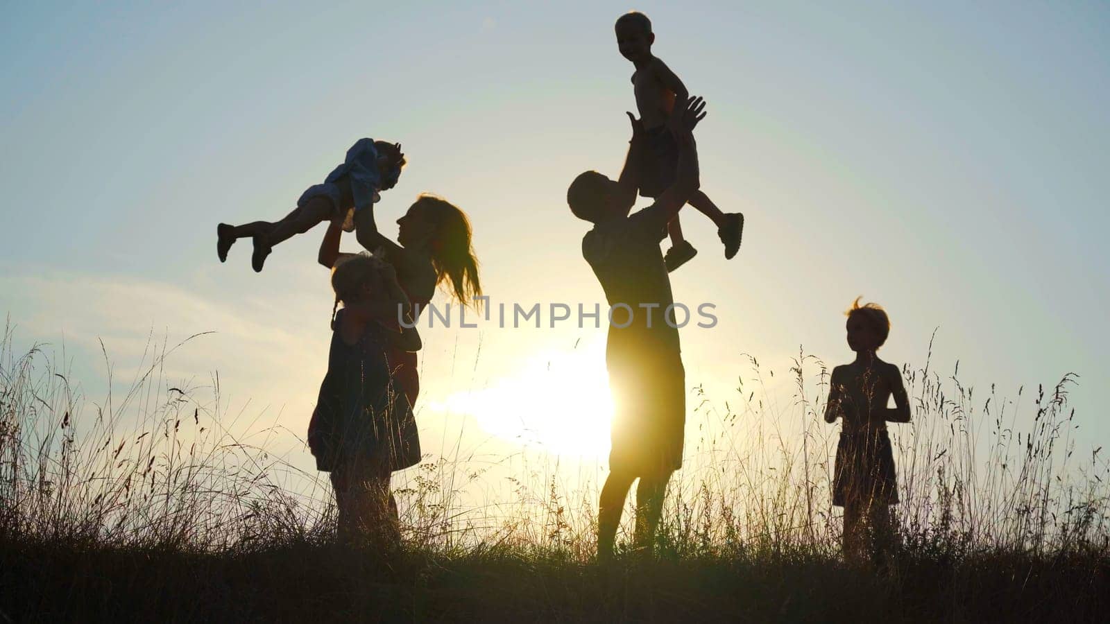 Happy parents circle their children against the sunset. by DovidPro