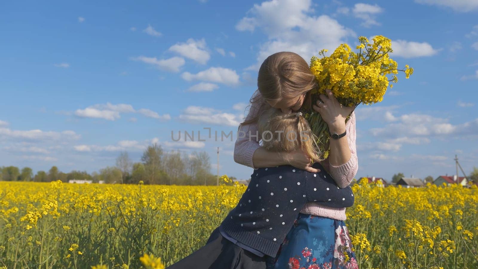 Grateful daughter gives her mother flowers in a rapeseed field
