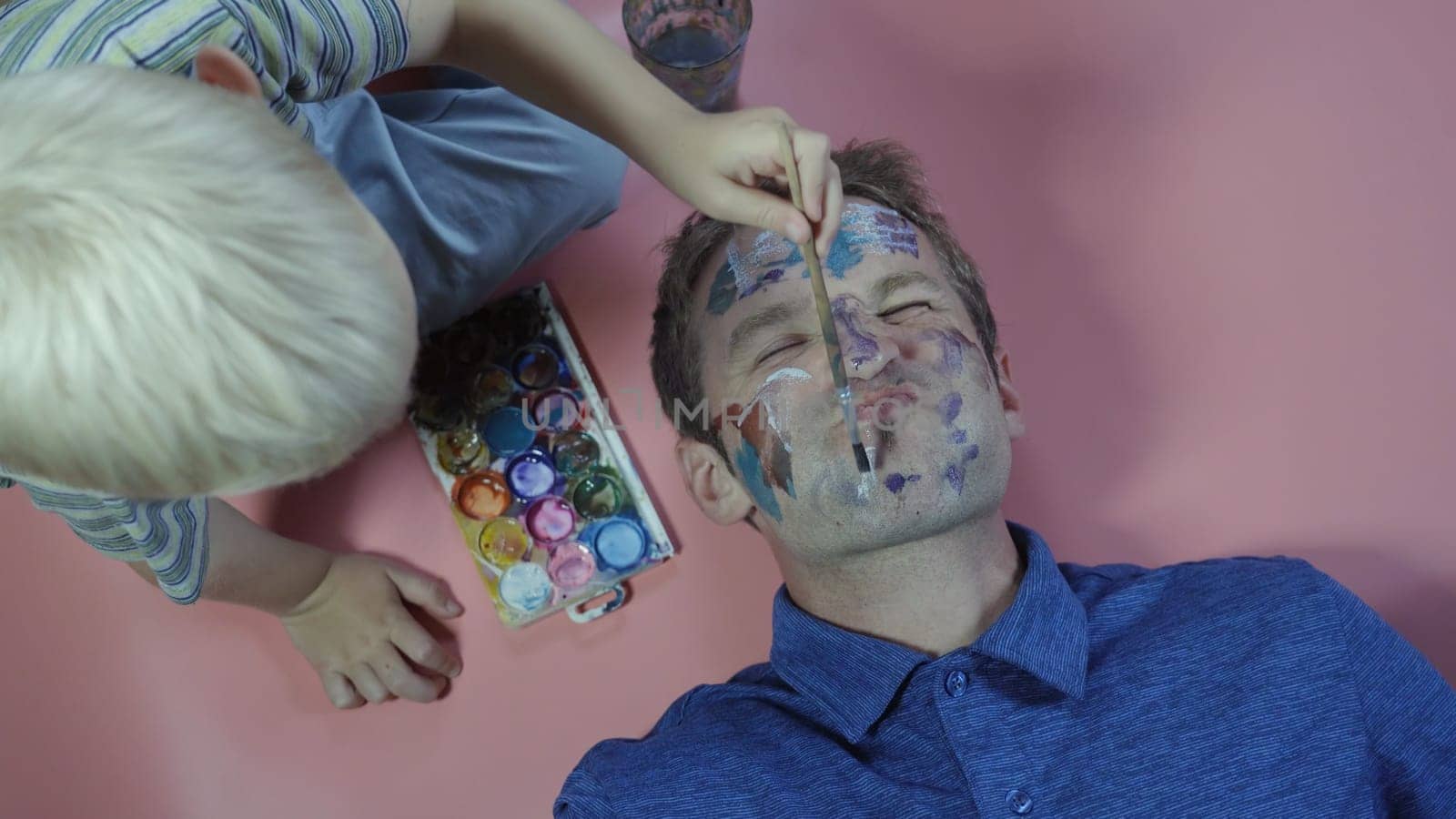 A cheerful father allows his child to paint the face