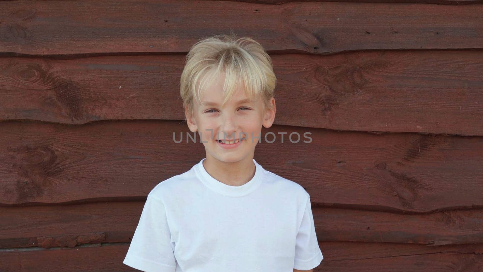 Portrait of an 8 year old boy at the wall of a barn in the village