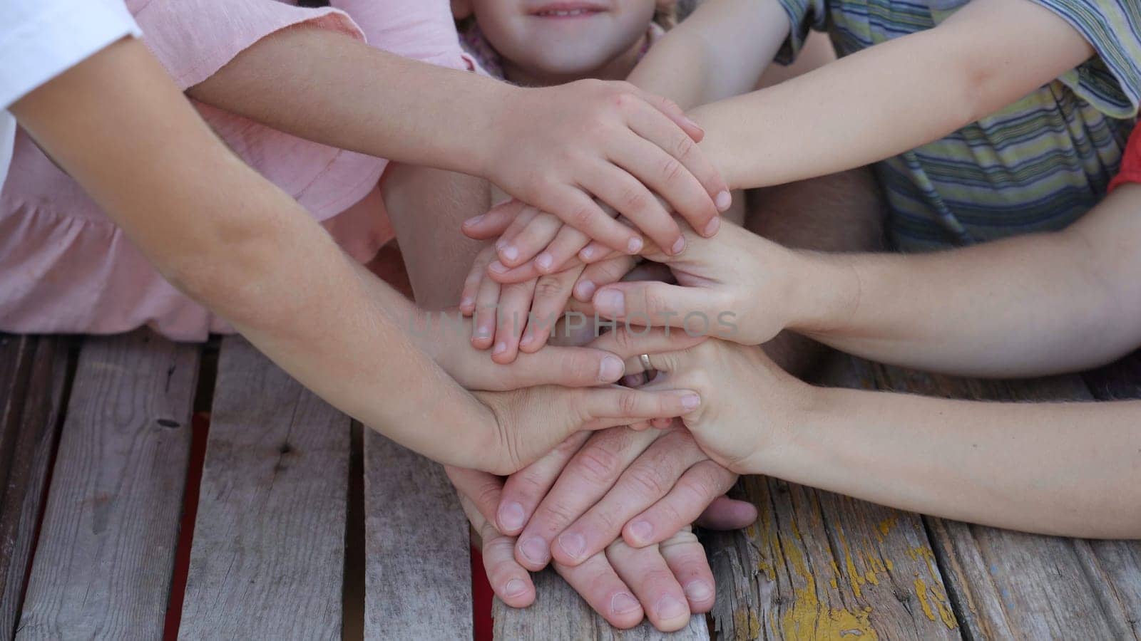 A friendly family joins their hands as a sign of joint success. by DovidPro