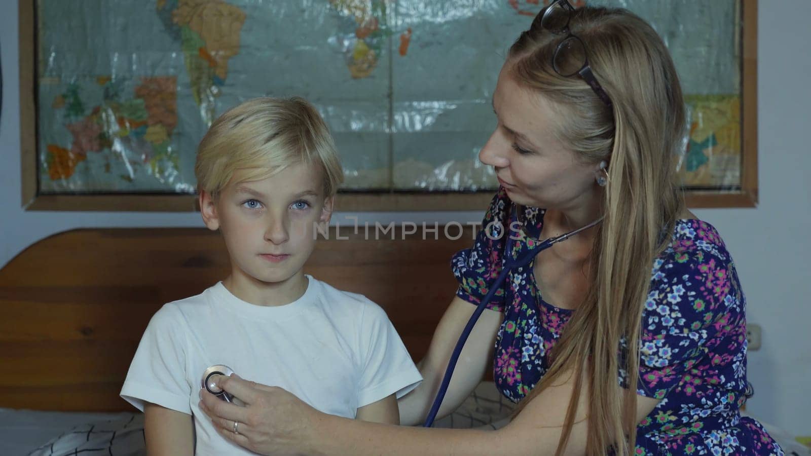 A caring mother listens to her son with stethoscope. by DovidPro