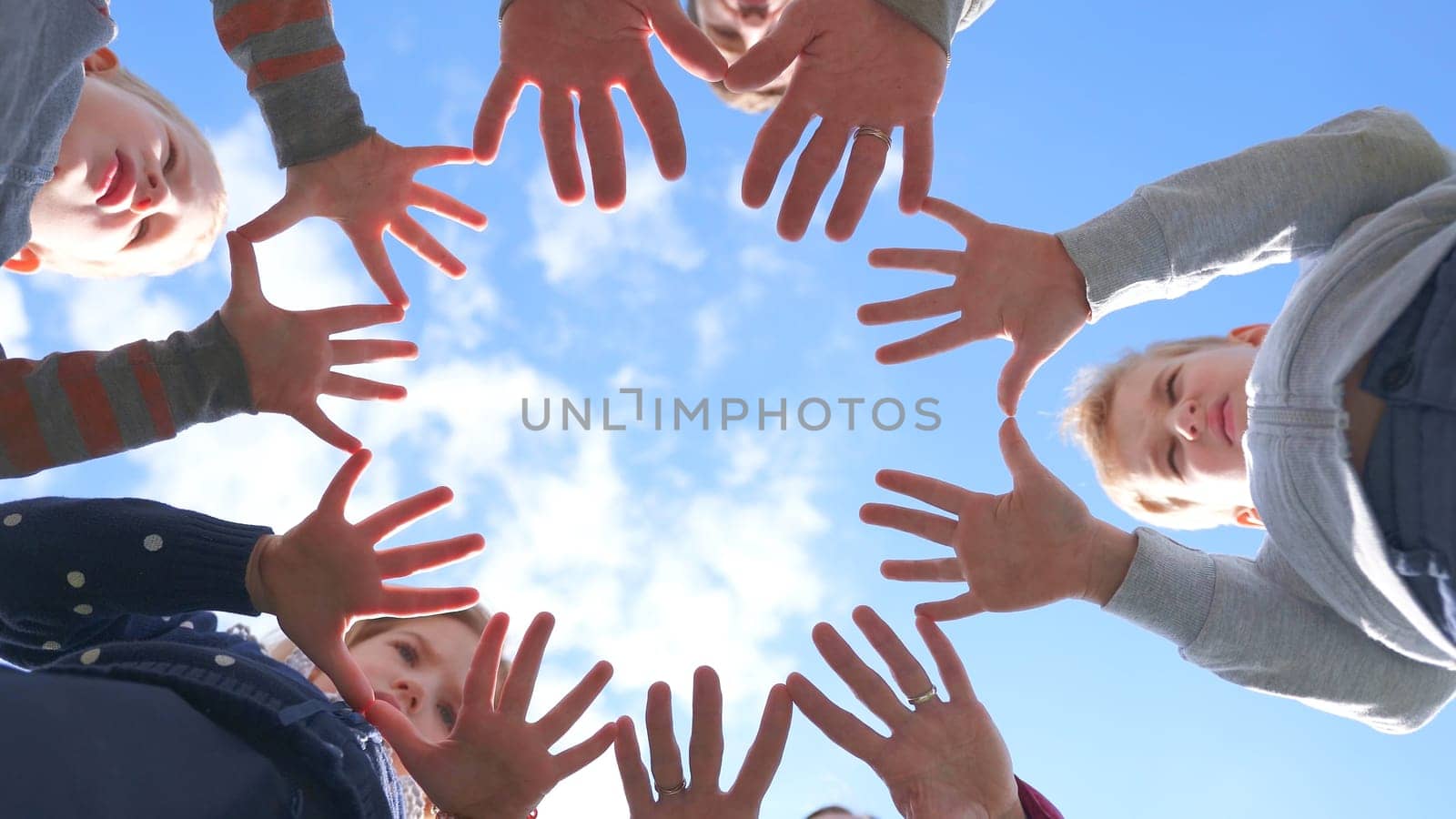 A friendly large family makes a circle shape out of the palms of their hands