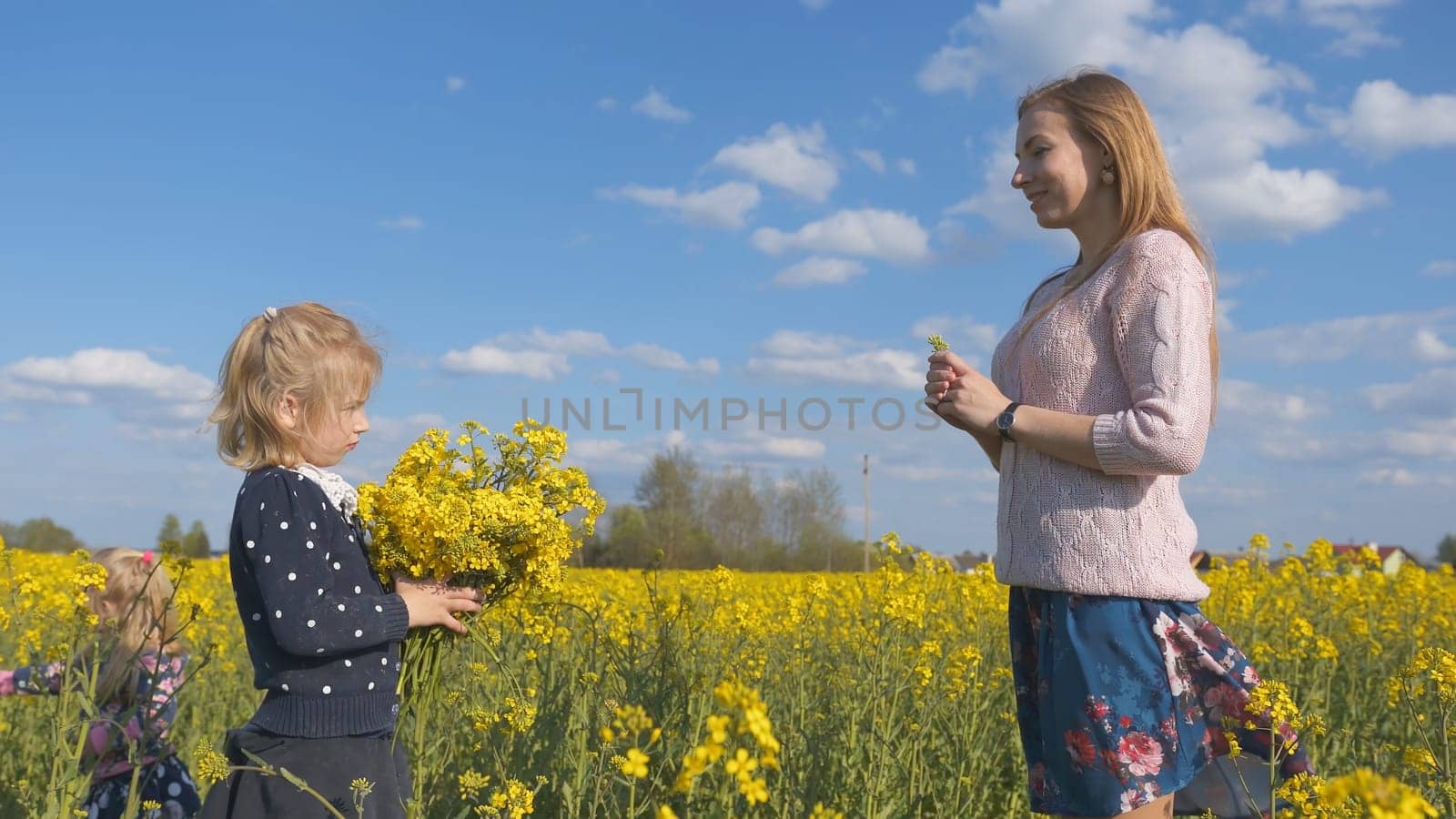 Grateful daughter gives her mother flowers in a rapeseed field