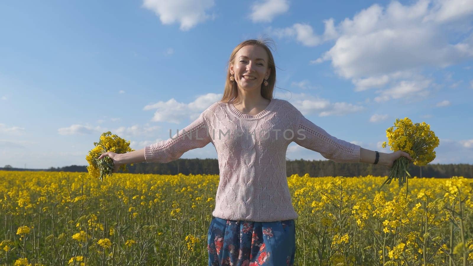 Happy girl with a bouquet of rapeseed flowers in a yellow rapeseed field