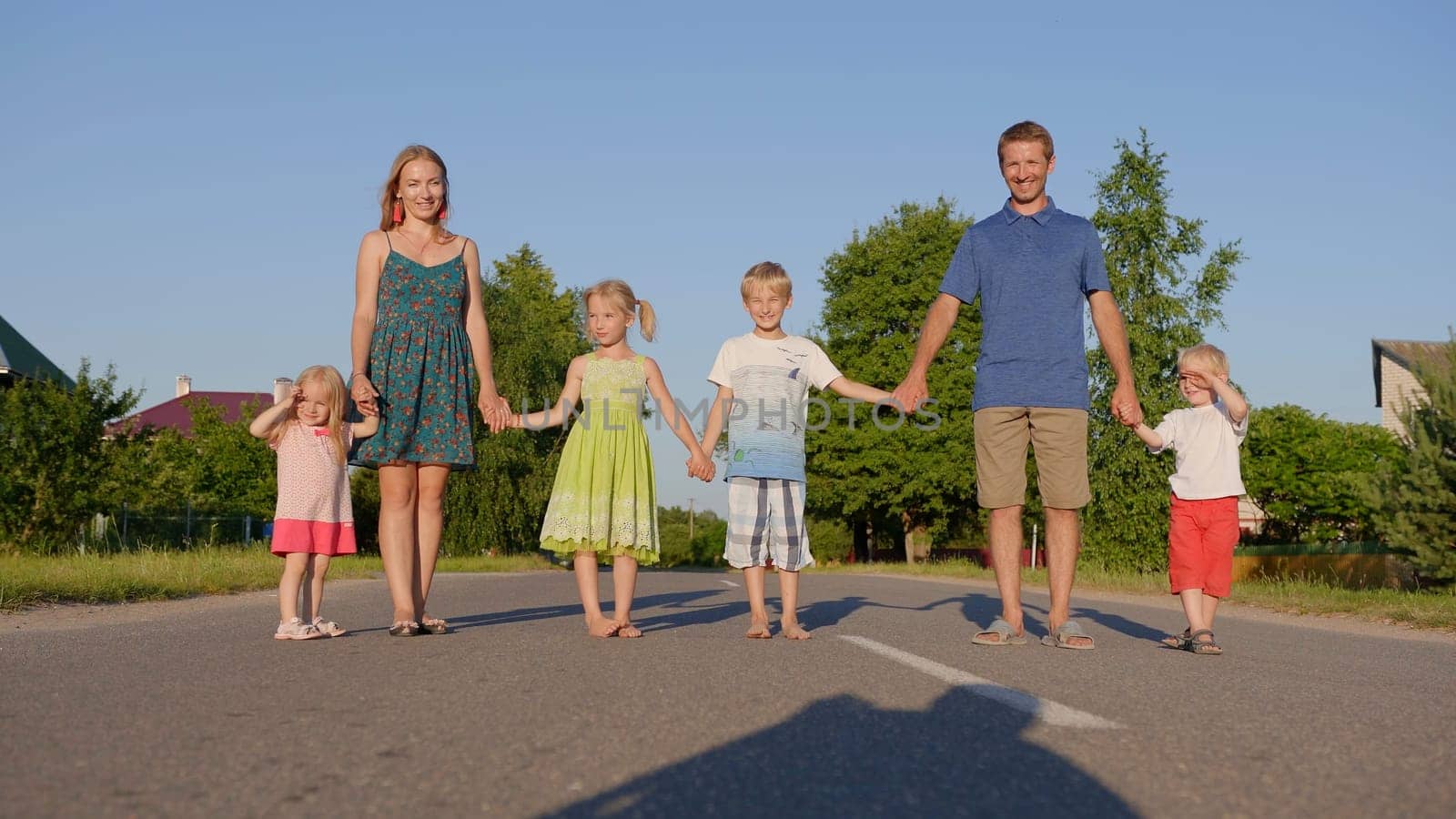 A strong friendly family holding hands is standing on the road