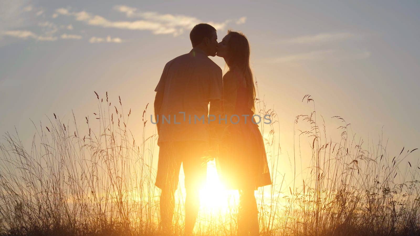 Silhouettes of happy lovers kissing at sunset