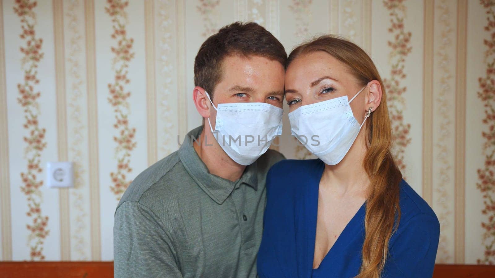 Home quarantine concept. Spouses kiss at home in a mask. by DovidPro