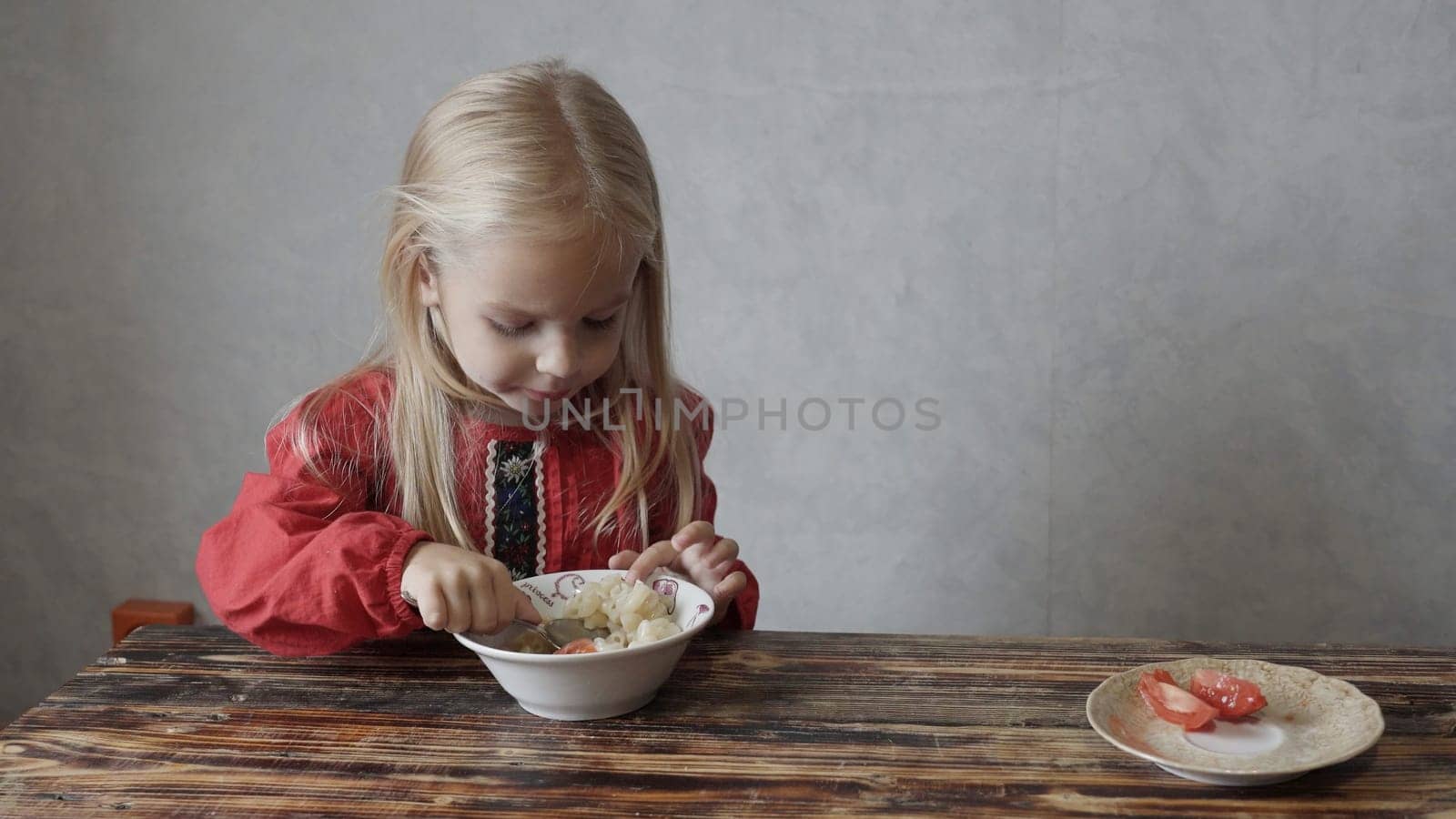 Little beautiful girl eats pasta at home