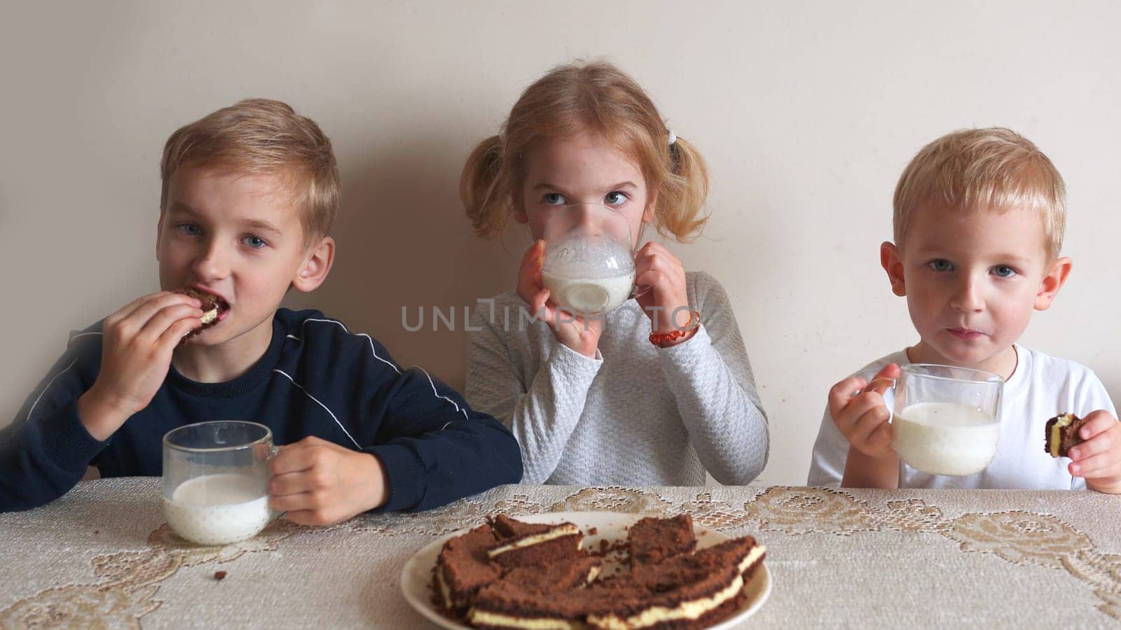 Children at the table eat milk and cookies. by DovidPro