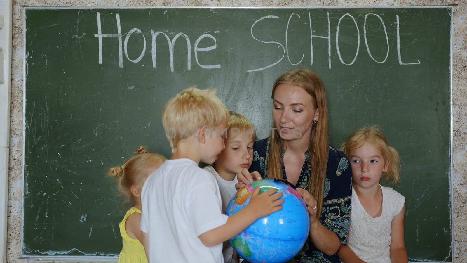 Home school concept. A mother gives her children a geography lesson with a globe in her hands. by DovidPro