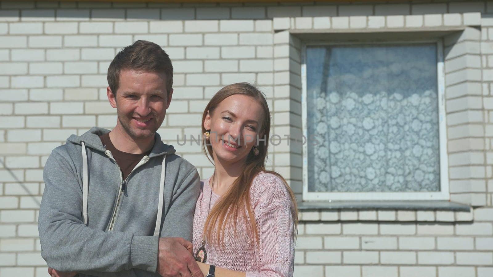 Young happy spouses on the background of their home. by DovidPro