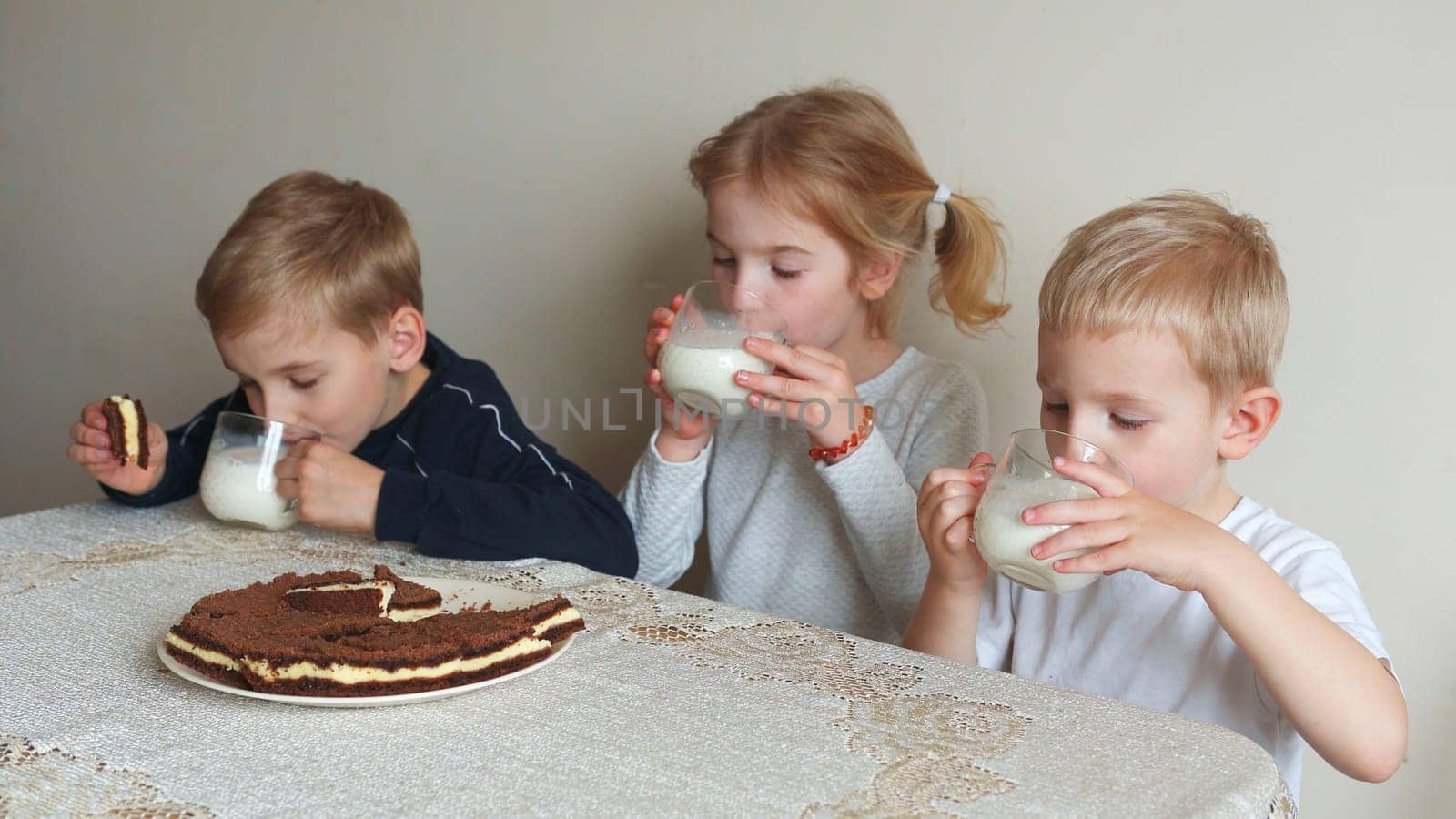 Children at the table eat milk and cookies