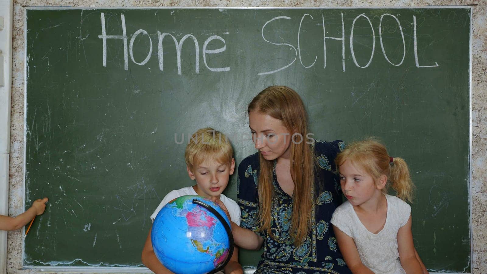 Home school concept. A mother gives her children a geography lesson with a globe in her hands