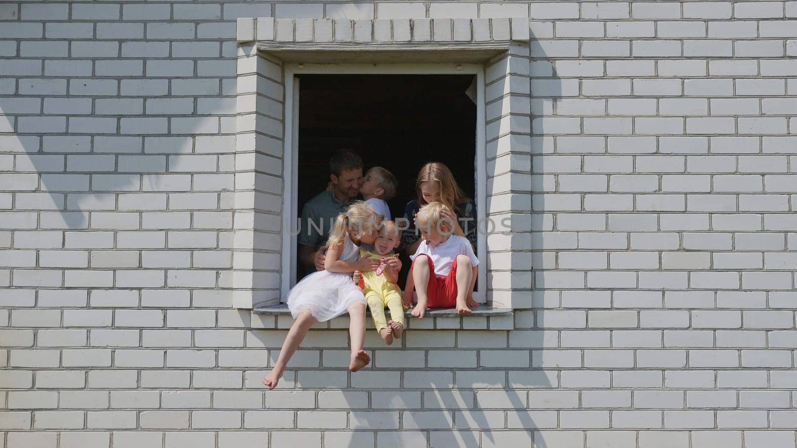 The concept of a large family. A friendly family hugs each other in the window of their house. by DovidPro