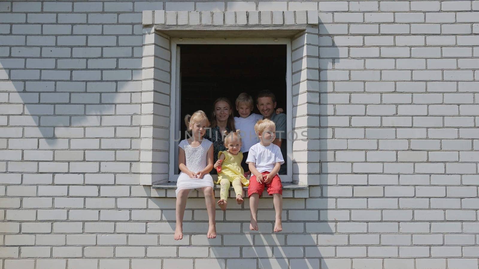 A friendly family appears in the window of their house. by DovidPro