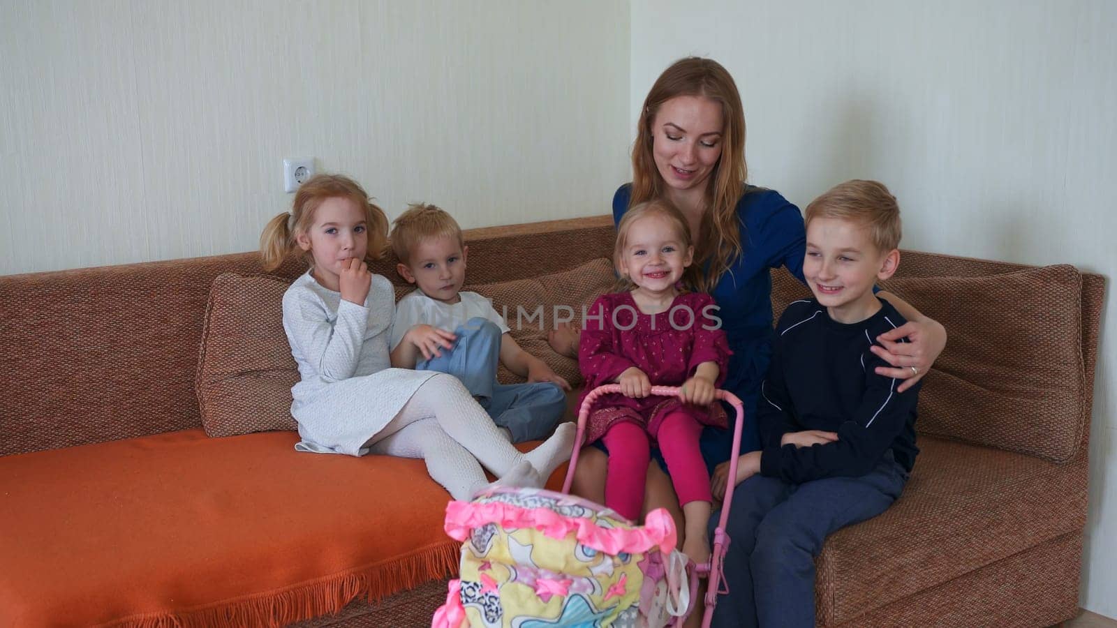 Happy mother of many children with her children on the couch in the house