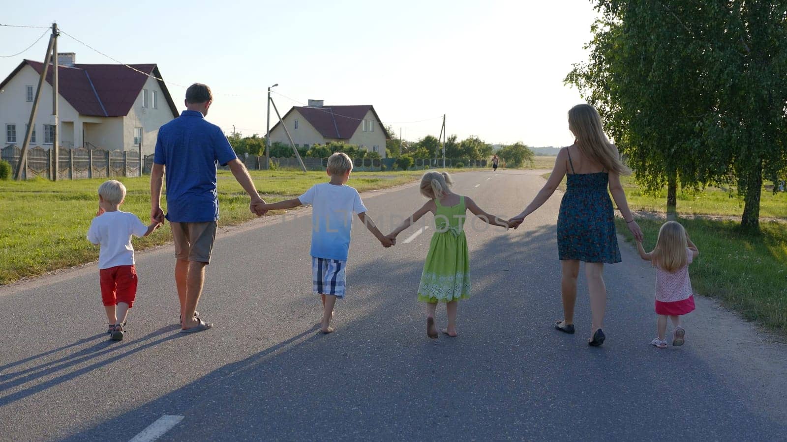 Strong friendly family holding hands goes along the road. by DovidPro