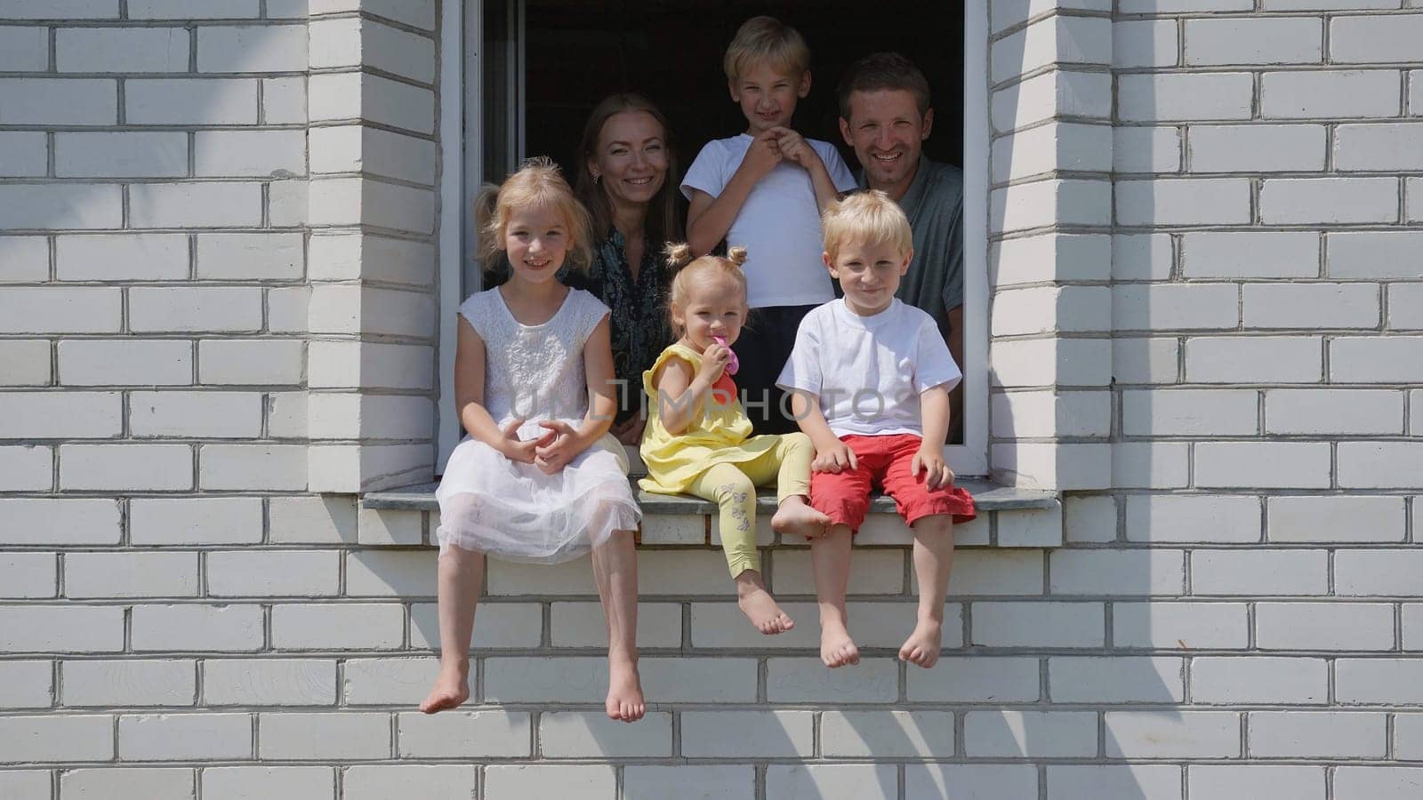 A large large family poses from the window of their home. by DovidPro