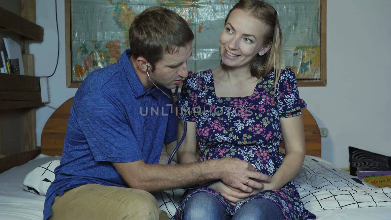 A loving husband listens to the belly of a pregnant wife with a stethoscope. by DovidPro