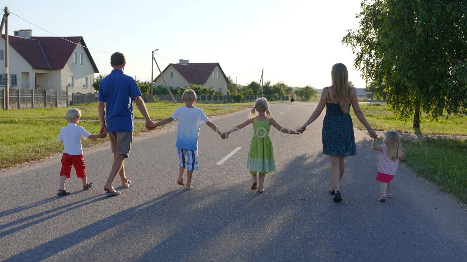 Strong friendly family holding hands goes along the road