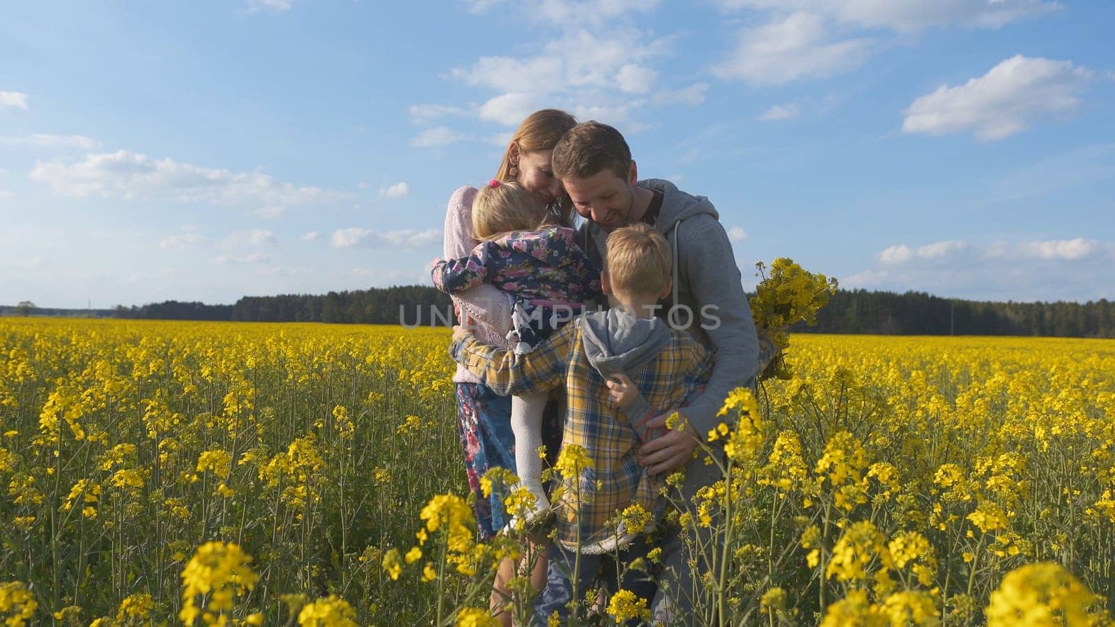Happy family hugs in a rapeseed field