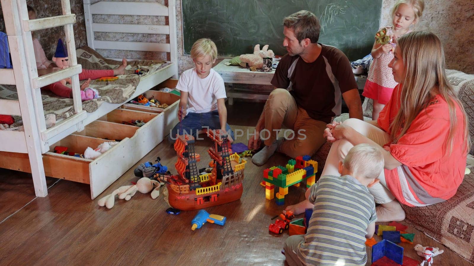 A friendly family with children playing toys at home. by DovidPro