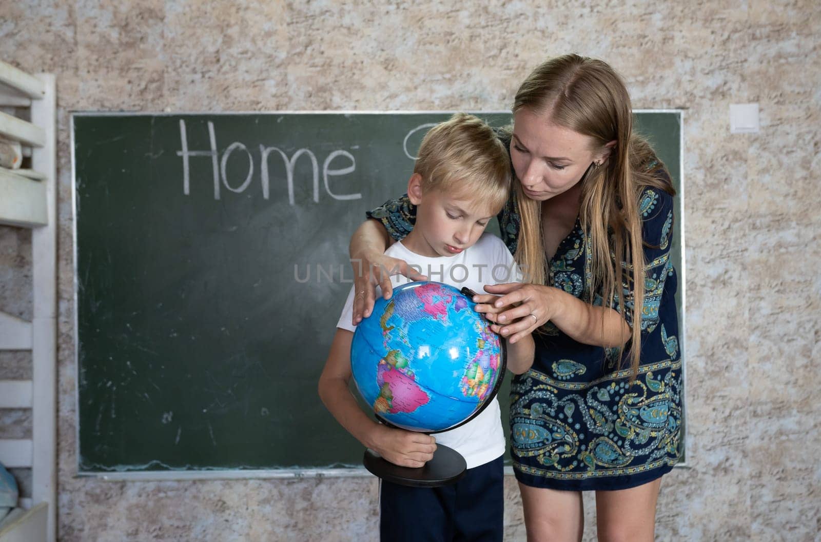 Mother is studying a world map on a globe with her son