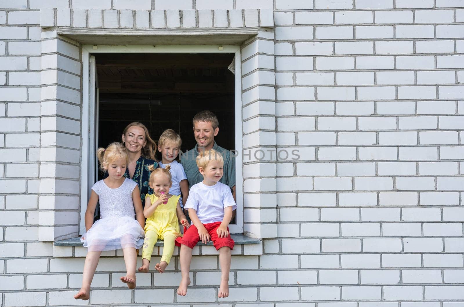 A large large family poses from the window of their home. by DovidPro